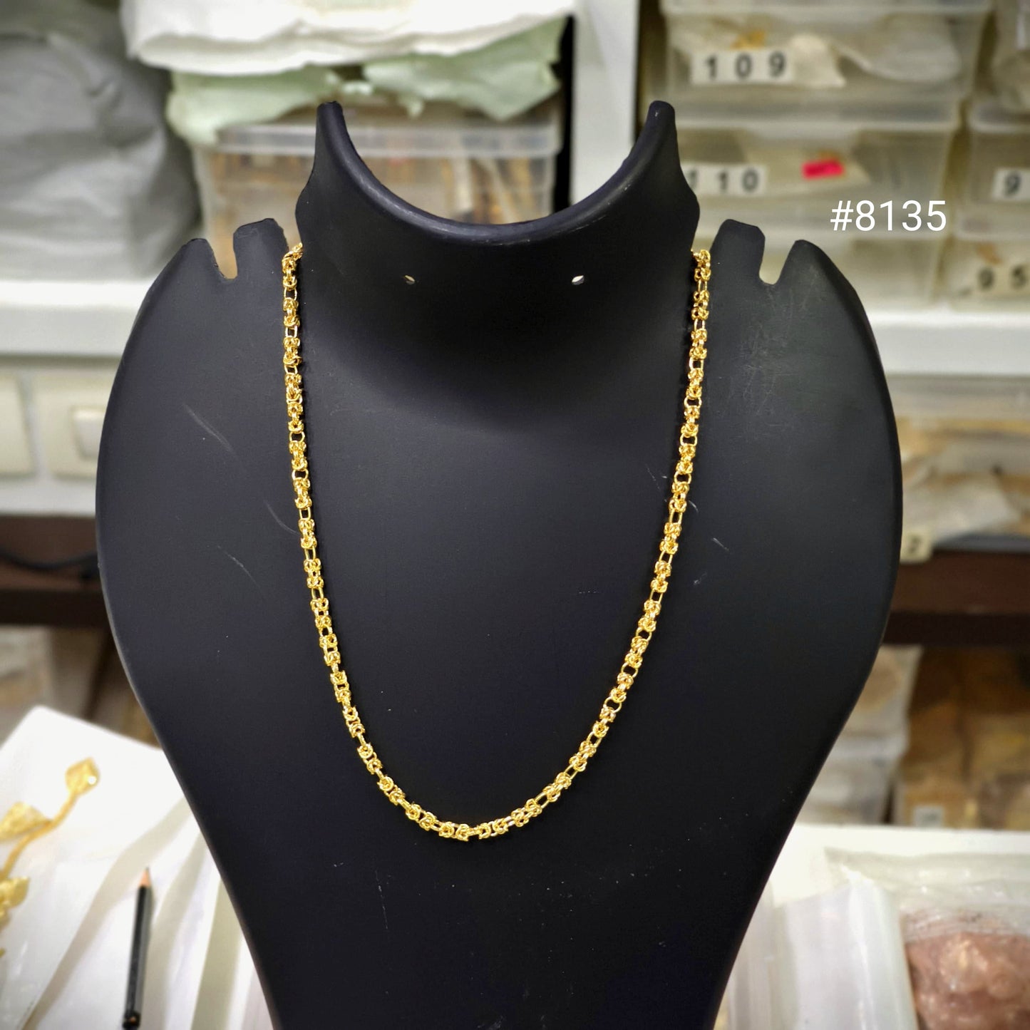 Gold chain necklace on a black mannequin bust with a blurred background