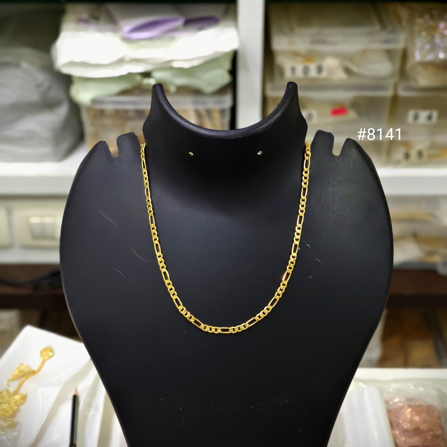 Gold chain necklace on a black mannequin bust with a blurred background