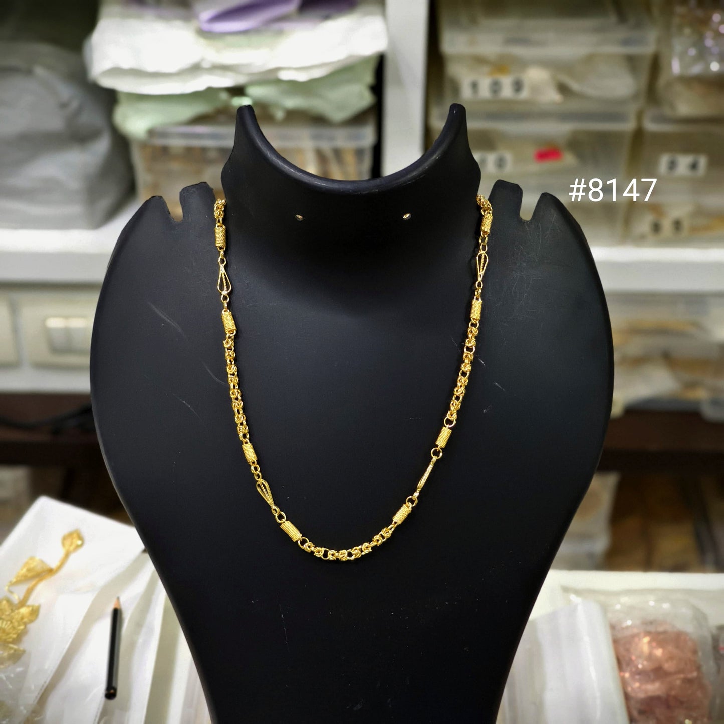 Gold chain necklace on a black mannequin bust with a blurred background