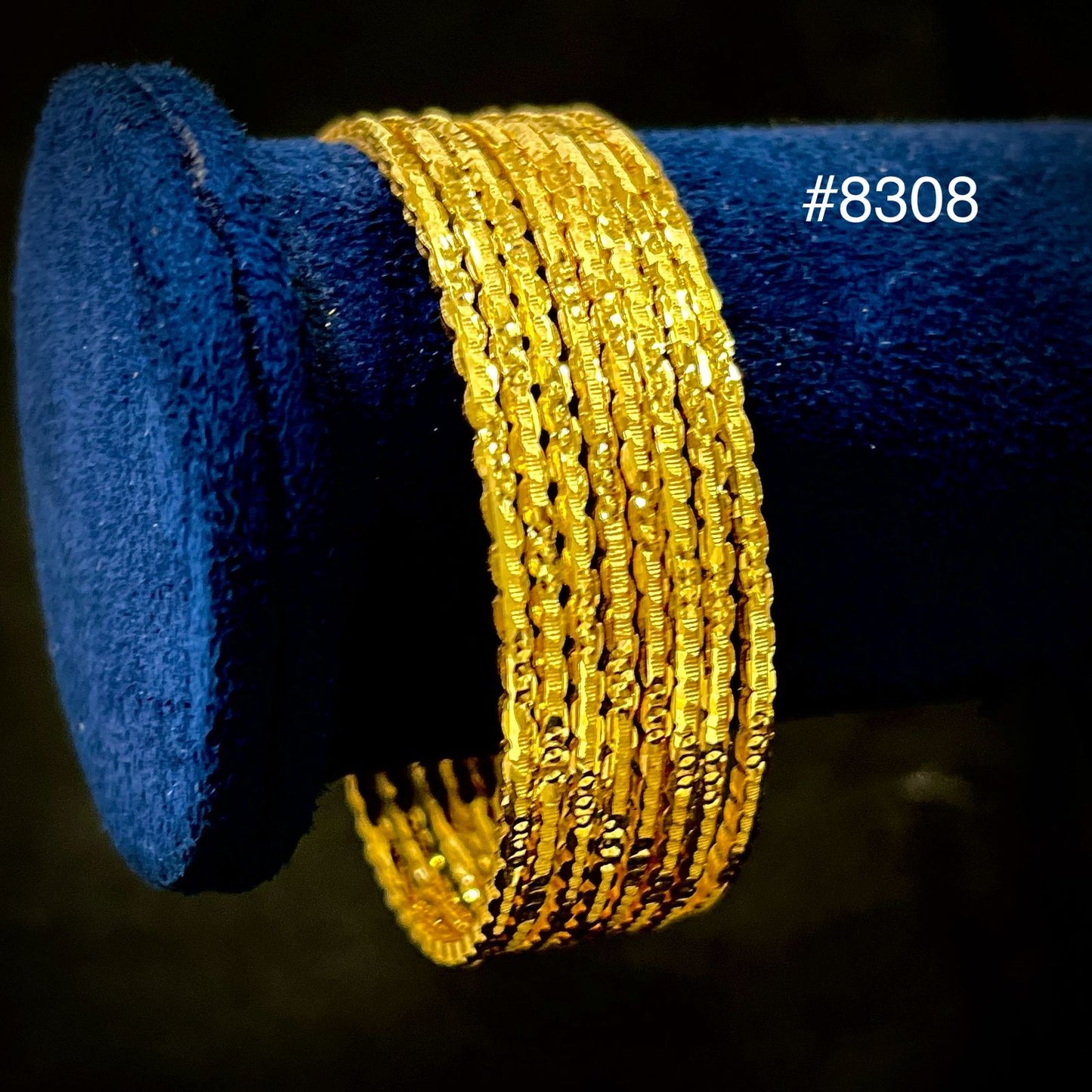 Gold bangles on a blue cushion with a dark background