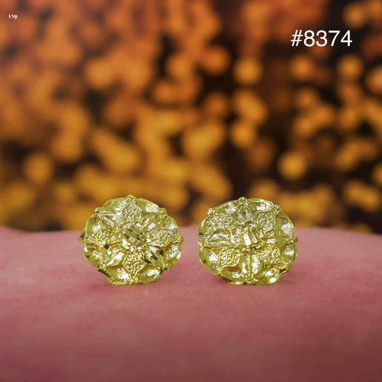 Gold earrings on a pink surface with a blurred gold background