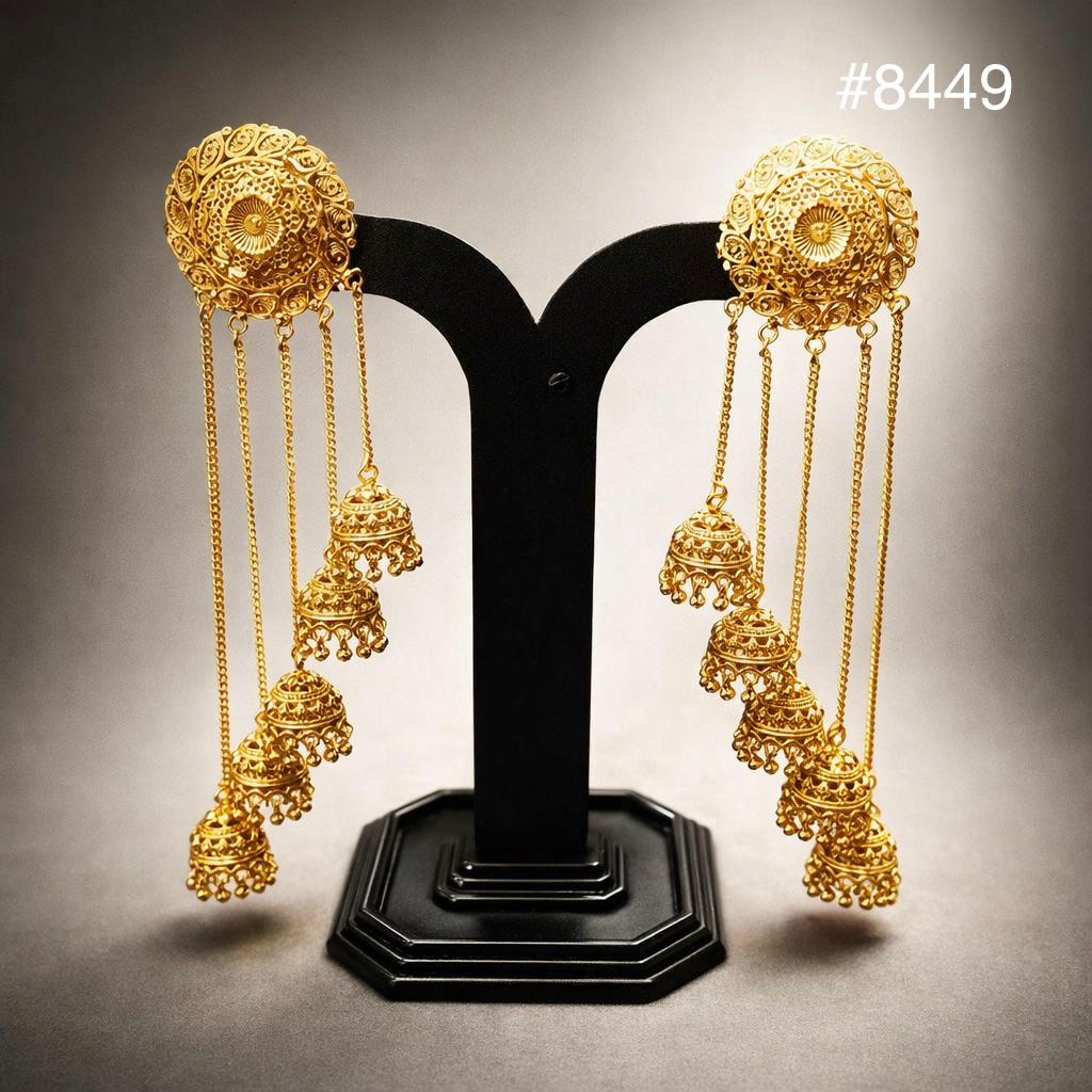 Ornate gold chandelier jhumka earrings with round filigree tops and dangling bells, displayed on a black stand; elegant, luxurious jewelry.
