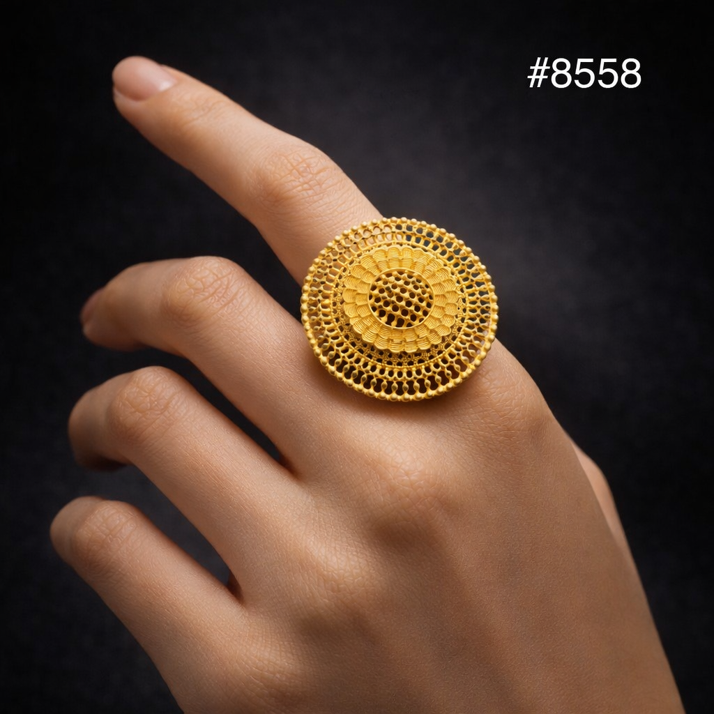 Close-up of a hand wearing an ornate round gold ring with concentric filigree circles against a black background; elegant, refined tone.