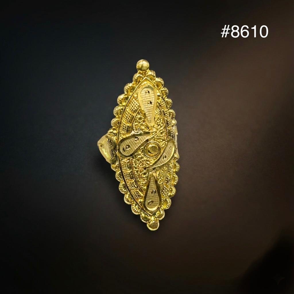 Ornate gold, vertically elongated jeweled brooch or pendant with intricate filigree and raised decorative motifs, displayed against a dark background.