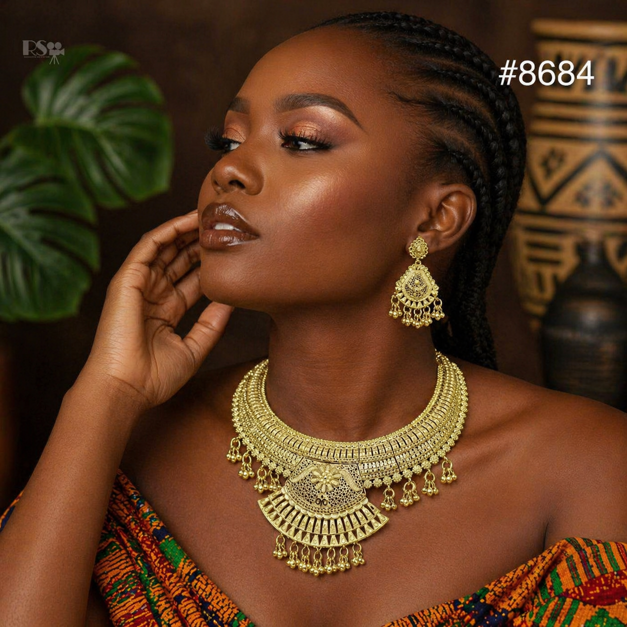 Close-up portrait of a Black woman with braided hair, wearing ornate gold jewelry and vibrant patterned clothing, posed confidently in warm light.