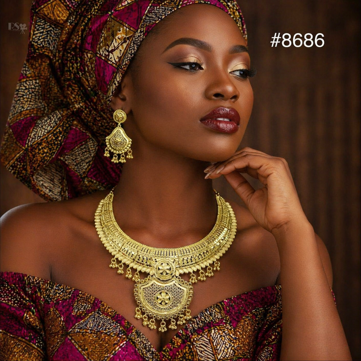 Elegant Black woman in vibrant Ankara headwrap and dress, wearing ornate gold jewelry, poses thoughtfully against a dark backdrop; #8686.