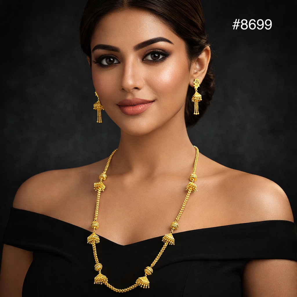 A woman wearing an off-shoulder black top and gold necklace with matching earrings, posed against a dark background with the number 8699 in the upper right corner.