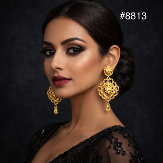A woman with dark hair in a low bun wears ornate gold earrings and a black lace outfit. She has bold makeup with red lipstick and dark eye shadow. The background is dark, and the number #8813 appears in the corner.