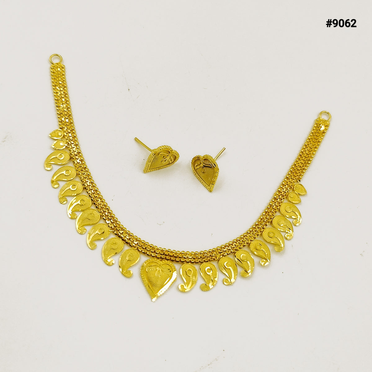 Gold necklace and matching earrings displayed on a white background, featuring ornate textured chains and dangling heart-shaped charms; elegant jewelry set.
