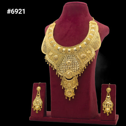A large, ornate gold necklace with intricate patterns is displayed on a burgundy stand, accompanied by matching dangling earrings. The set is labeled with the number #6921 on a black background.