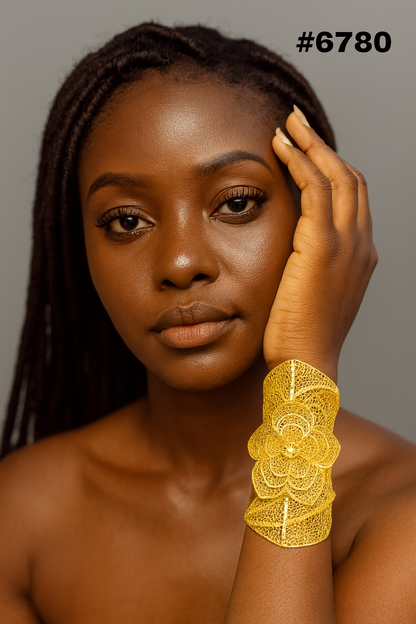 Close-up portrait of a poised Black woman with locs, resting her hand on her face and wearing an ornate gold cuff bracelet; warm, elegant mood.