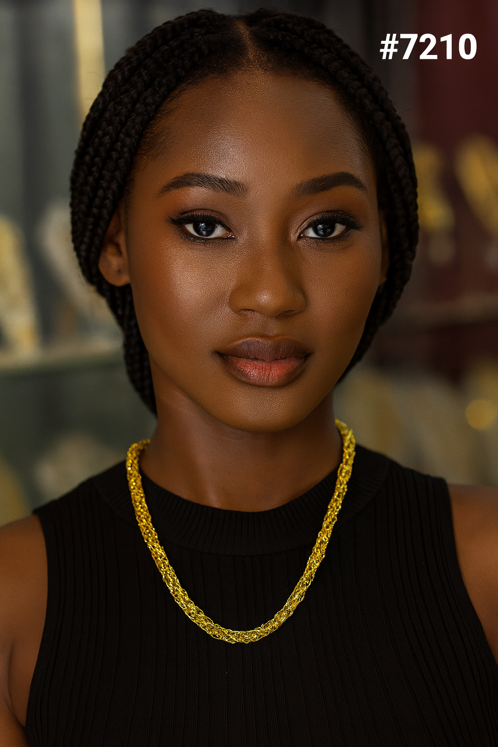 Close-up portrait of a confident Black woman with braided hair, wearing a black top and gold chain necklace, gazing calmly at the camera. #7210