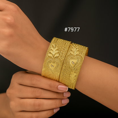 Gold bracelet with intricate designs on a wrist against a dark background