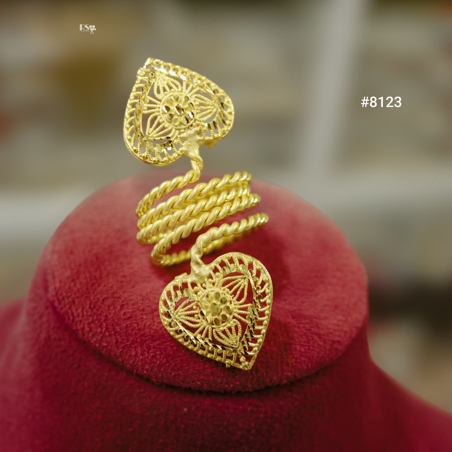 Gold heart-shaped earring on a red cushion with a blurred background