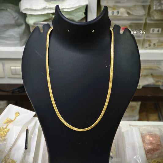 Gold necklace on a black mannequin bust with a blurred background