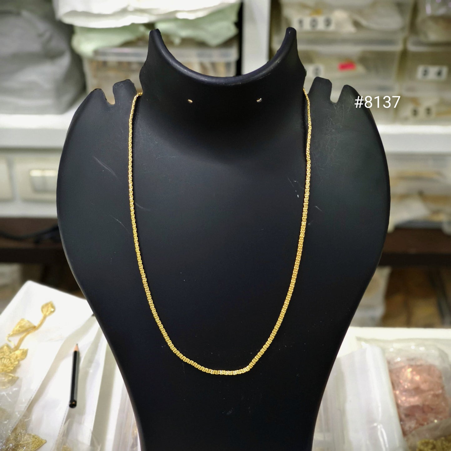 Gold necklace on a black mannequin bust with a blurred background