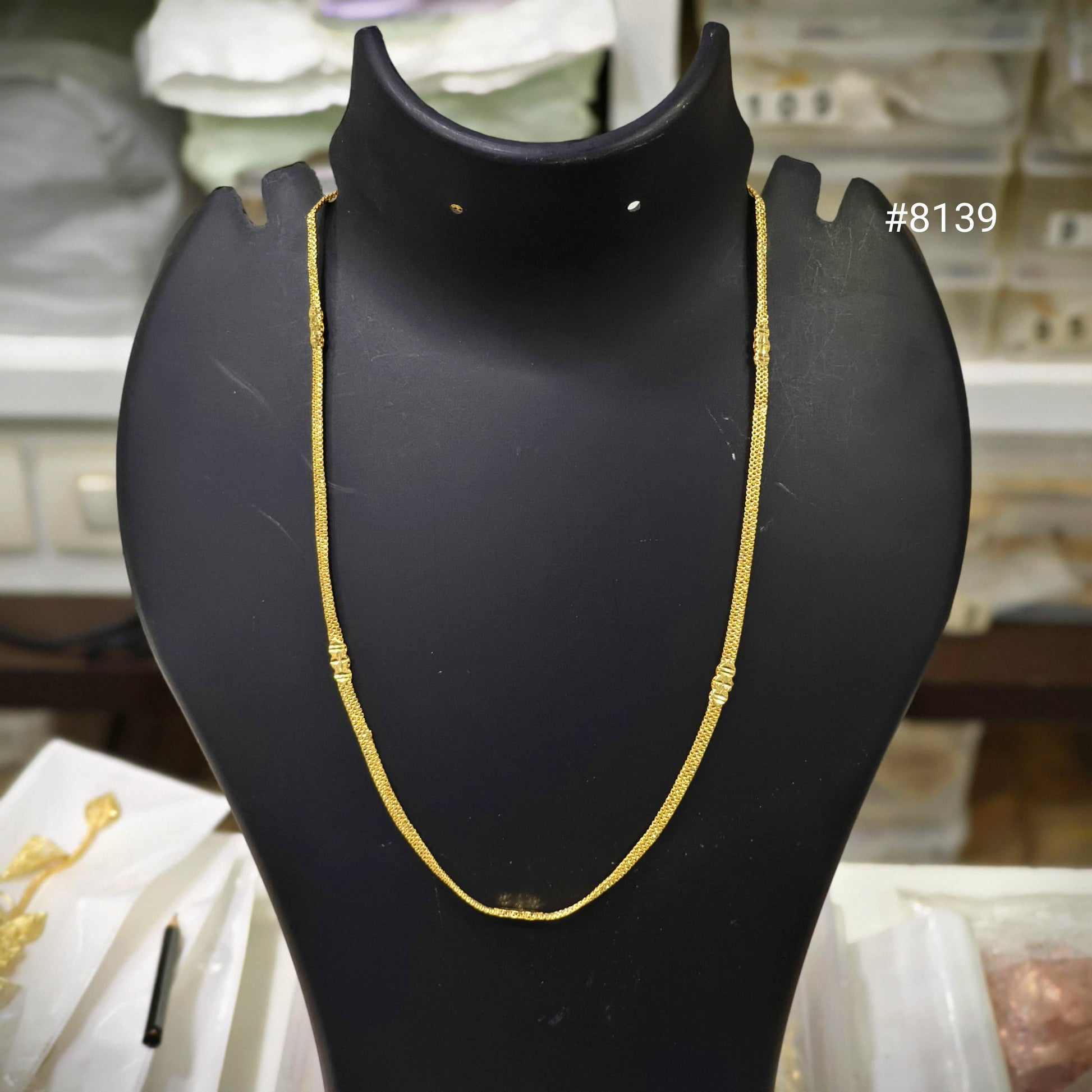 Gold necklace on a black mannequin bust with a blurred background