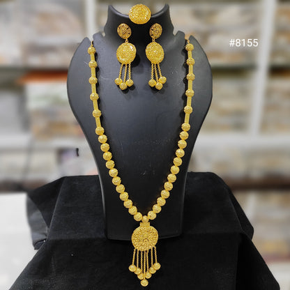 Gold necklace and earrings set on a black mannequin bust with a blurred background.