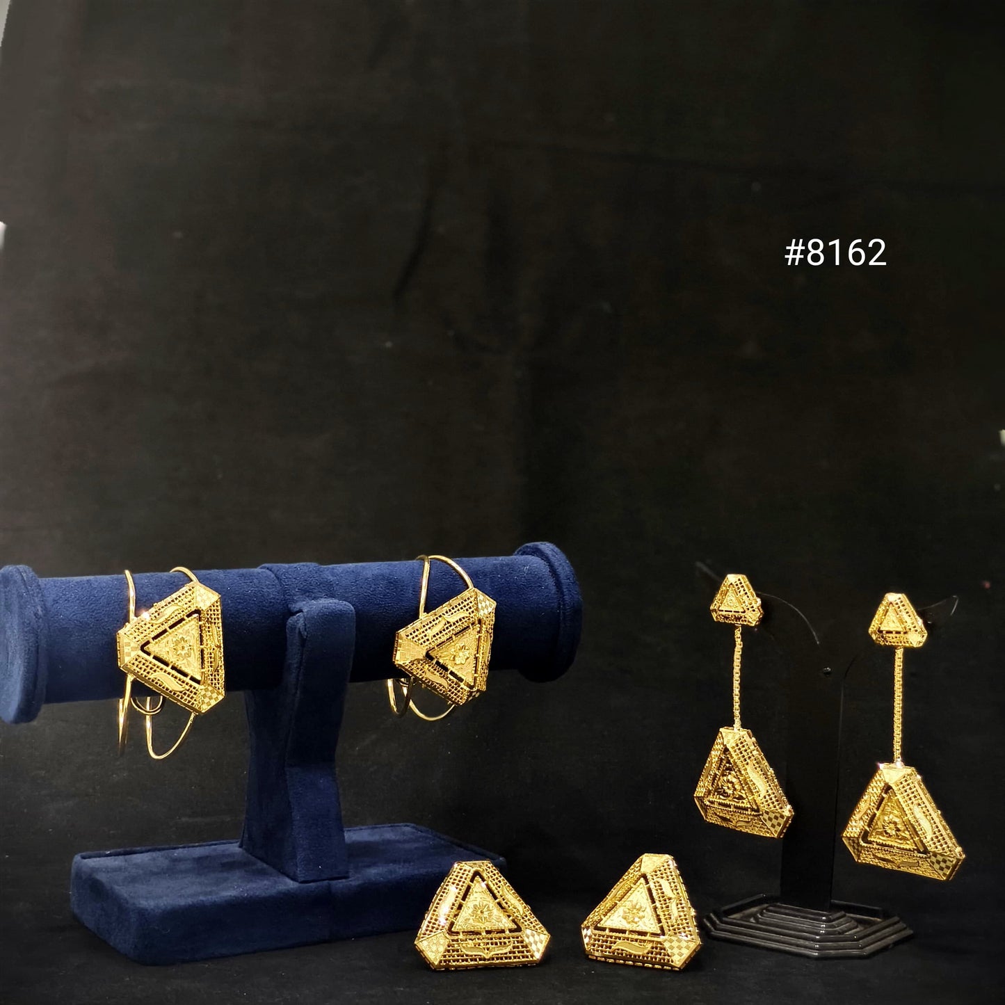 Gold geometric earrings on a black background with geometric braclet pair and geometric earrings pair