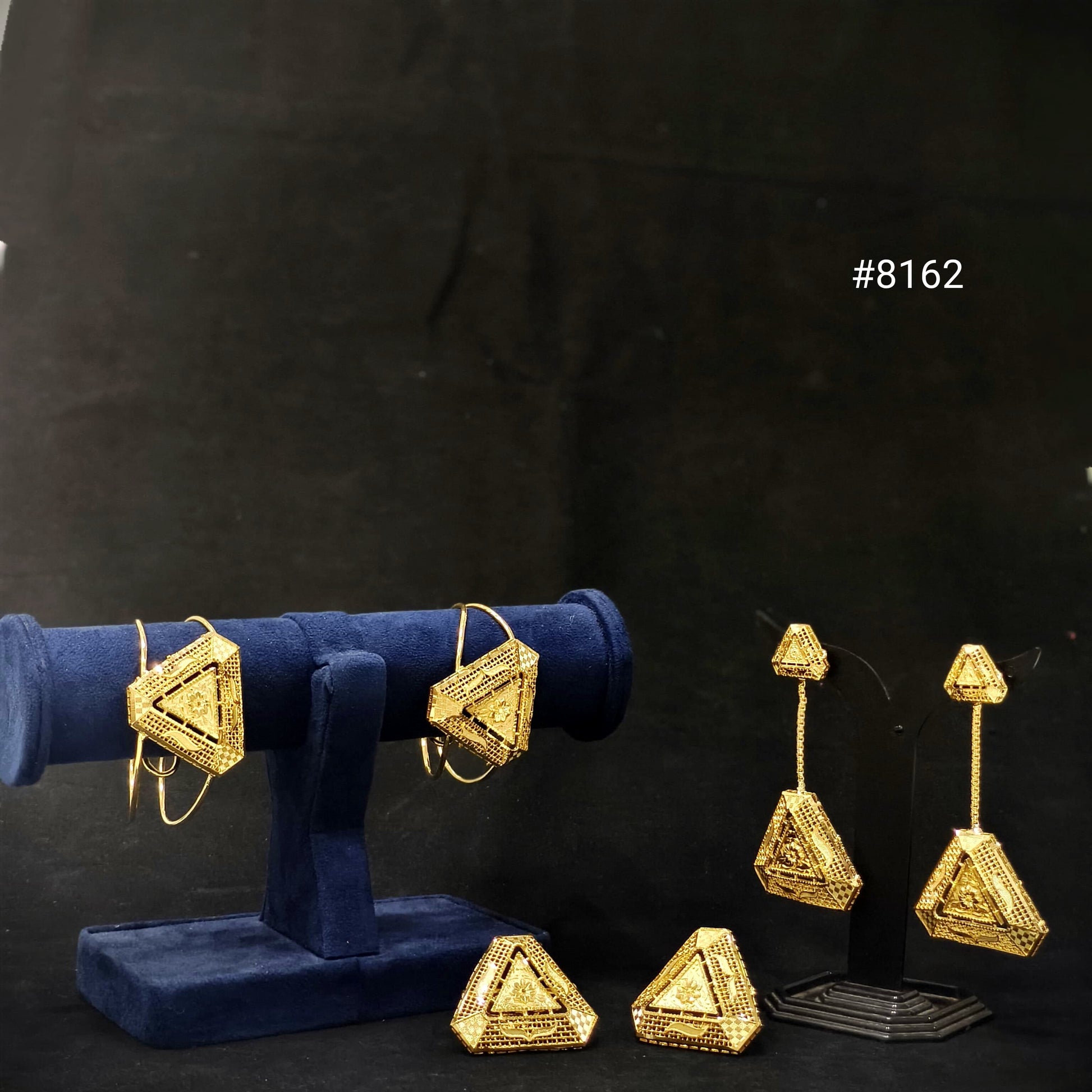 Gold geometric earrings on a black background with geometric braclet pair and geometric earrings pair