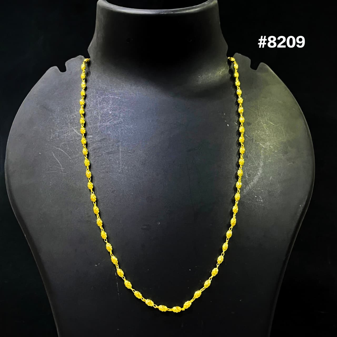 Yellow beaded necklace on a black mannequin with a dark background