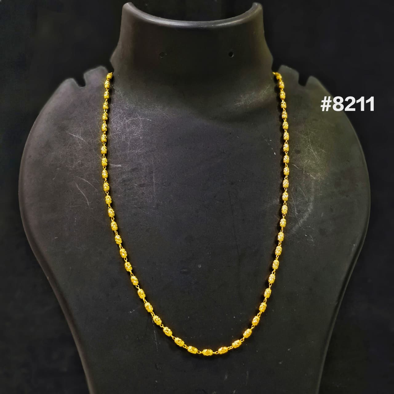 Gold necklace on a black mannequin with a dark background