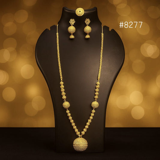 Gold necklace and earrings on a black stand with a blurred gold background