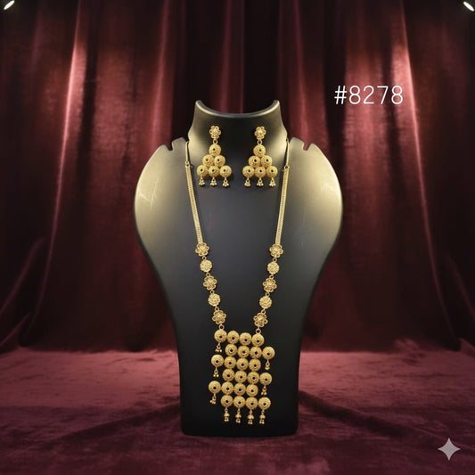 Gold necklace and earrings on a mannequin bust against a red curtain background