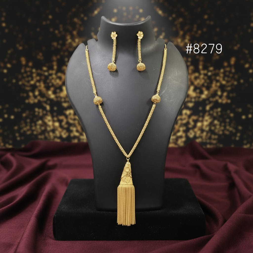 Gold necklace and earrings on a black mannequin with a dark background