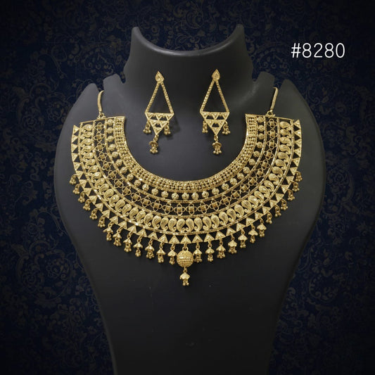 Gold necklace and earrings set on a black mannequin against a dark background