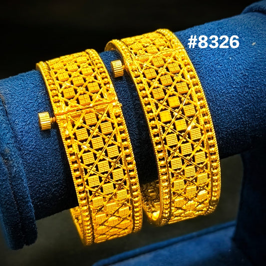 Two gold bracelets on a blue velvet stand with a visible brand number.