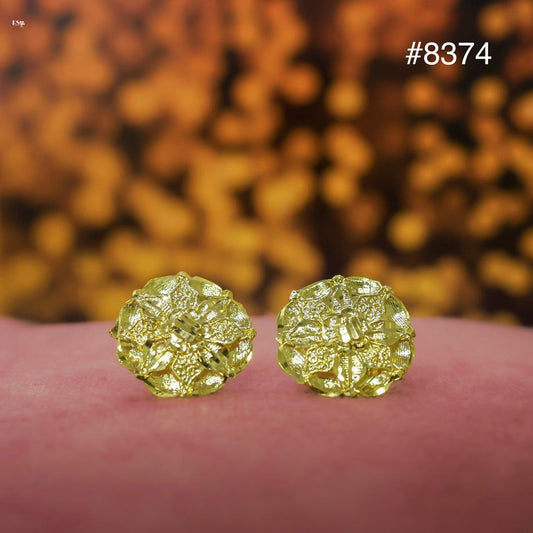 Gold earrings on a pink surface with a blurred gold background