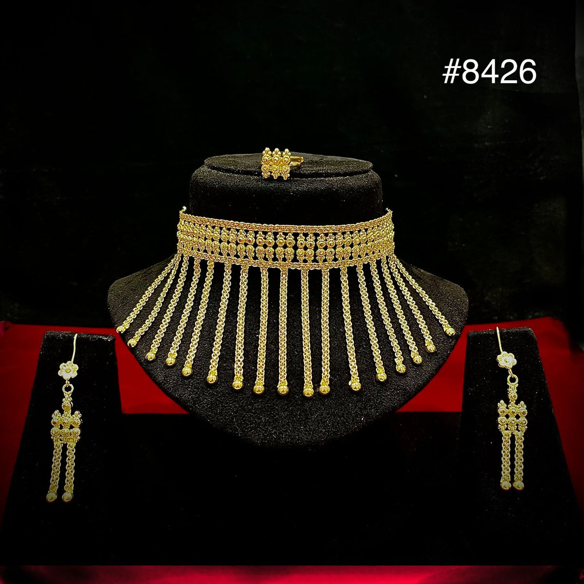 Ornate gold jewelry set #8426 displayed on black velvet: layered choker necklace with cascading chains, matching long earrings, and a ring.
