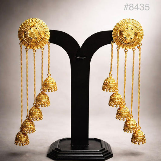 Pair of ornate gold jhumka earrings with floral tops and cascading bell charms, displayed on a black stand; traditional, elegant jewelry.