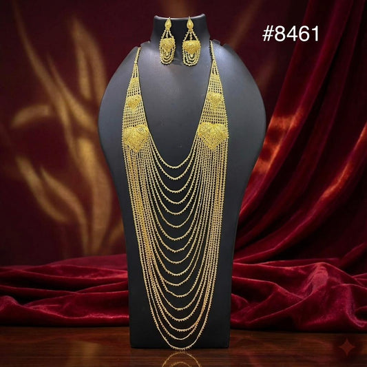 Gold layered necklace and matching earrings displayed on a black mannequin against red velvet drapery, creating an elegant tone. Style #8461.