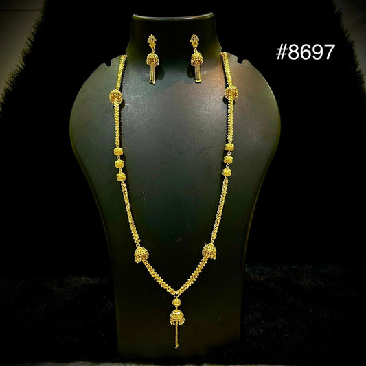 Gold jewelry set #8697 displayed on a black mannequin: long necklace with ornate pendant and matching dangling earrings, elegant and refined.