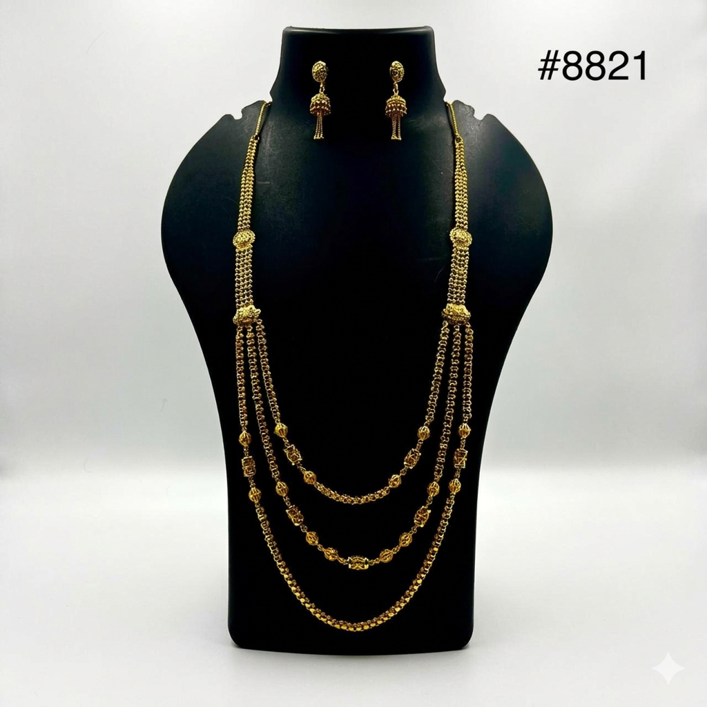 Elegant gold necklace and earrings set displayed on a black bust. The necklace features three layered chains with intricate bead patterns, exuding luxury.