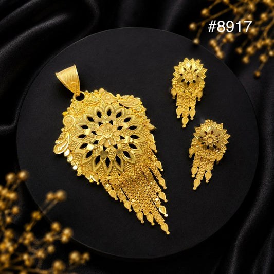 Ornate gold jewelry set with a filigree pendant and matching earrings on black velvet, showcasing intricate floral details and luxury.