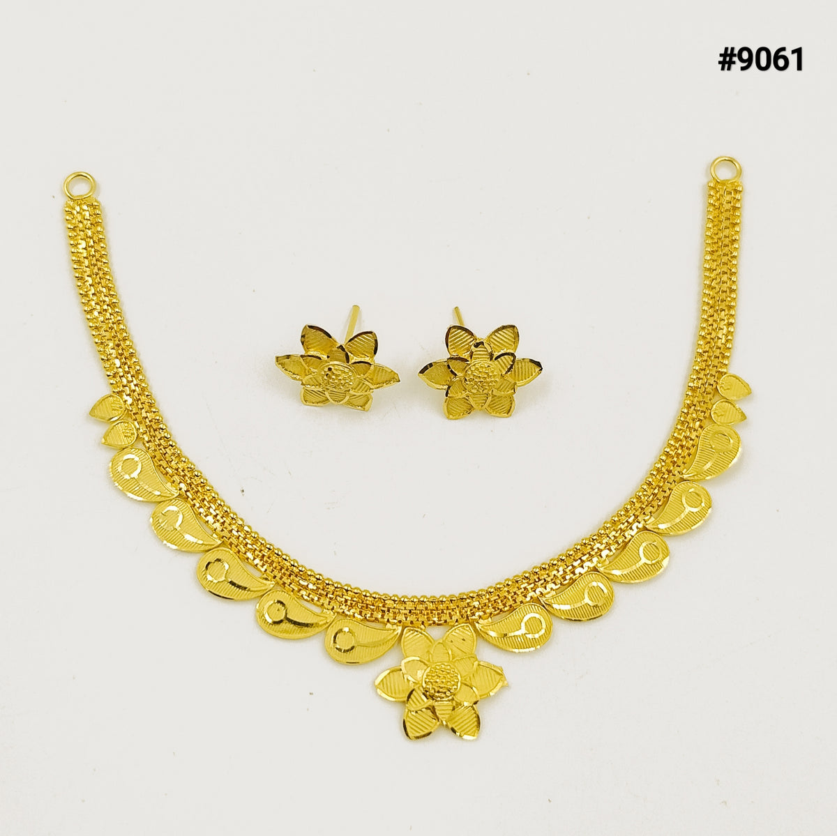 Gold-tone floral necklace with scalloped dangling charms and matching flower earrings, displayed on white; ornate, elegant jewelry set.