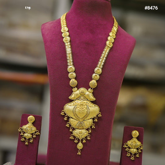 Ornate traditional gold necklace with large filigree pendant and matching earrings displayed on a burgundy mannequin, conveying luxury and heritage.