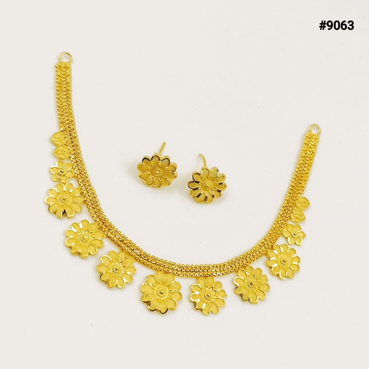 Gold-tone floral jewelry set with a linked necklace and matching flower earrings, arranged on a white background; elegant, delicate, festive style.