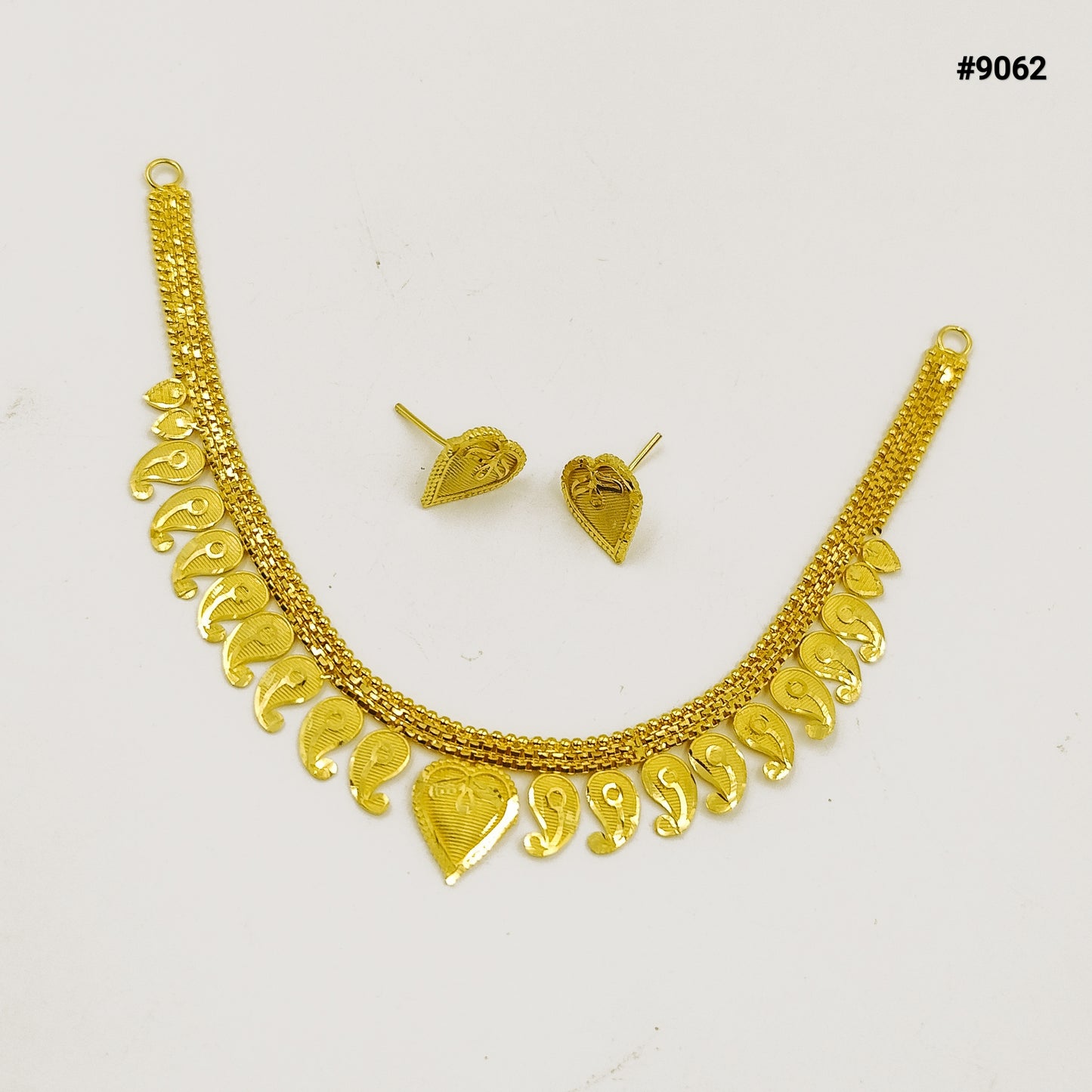 Gold necklace and matching earrings displayed on a white background, featuring ornate textured chains and dangling heart-shaped charms; elegant jewelry set.