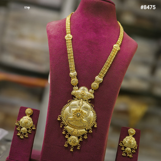 Ornate gold jewelry set on burgundy velvet: a long necklace with an elaborate pendant and matching dangling earrings, conveying luxury and tradition.
